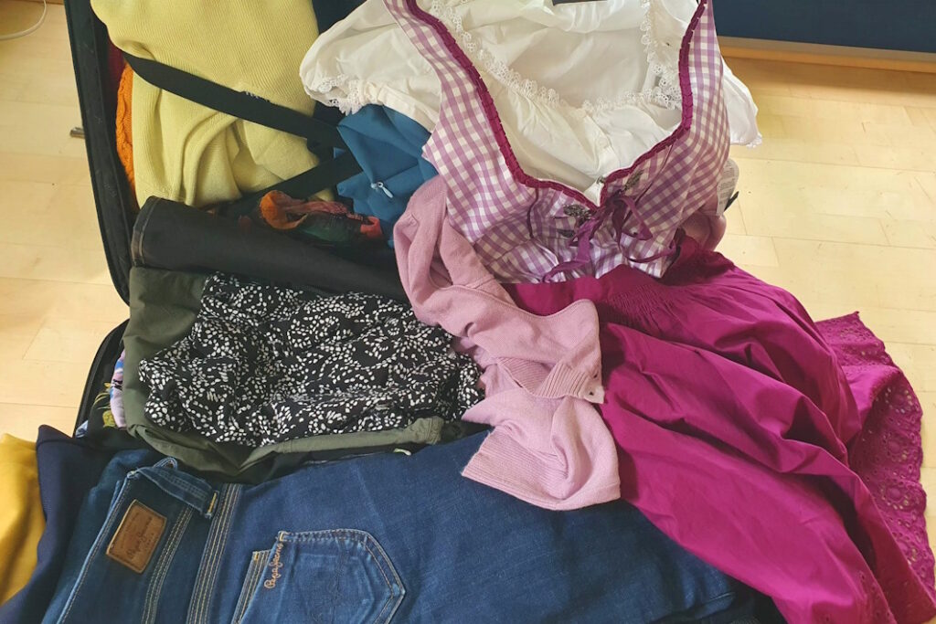 Kleidertauschkoffer Geöffneter Koffer mit Kleidungsstücken.