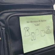 Koffer mit grünem Zettel, auf dem steht, Kleidertausch-Koffer.