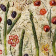 Ein Focaccia-Brot mit Gemüse in Form von Pflanzen und Blumen.