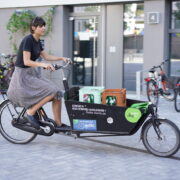 Eine Frau radelt auf einem Lastenrad durch die Stadt. Credits: fLOTTE Berlin