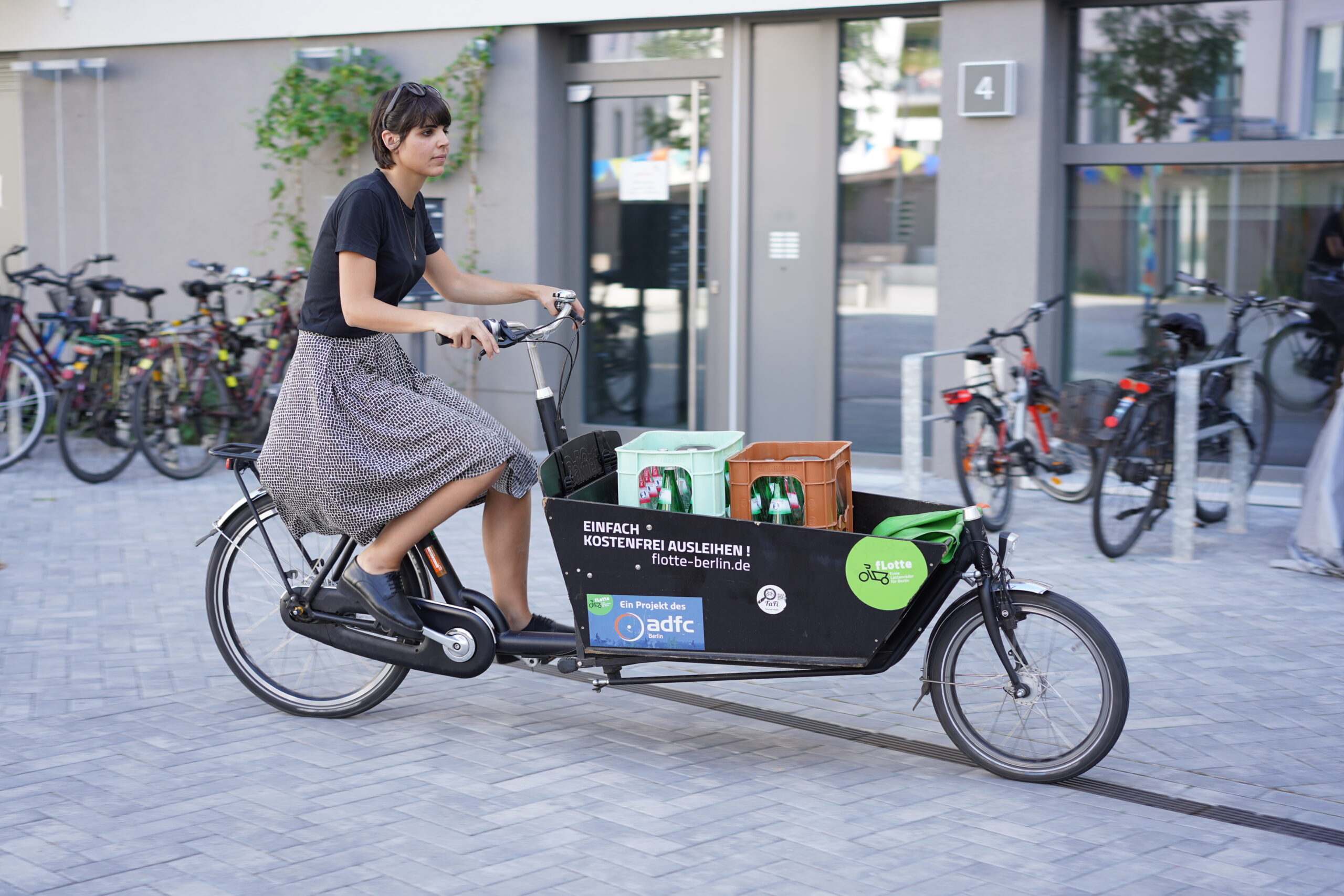 Eine Frau radelt auf einem Lastenrad durch die Stadt. Credits: fLOTTE Berlin