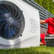 Ein Installateur kniet neben einer Wärmepumpe.