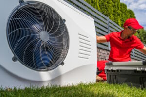 Ein Installateur kniet neben einer Wärmepumpe.