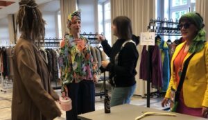 vier Frauen probieren bei einer Kleidertauschparty neue Styles aus