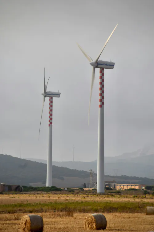 Zwei Windkraftanlagen auf einem Feld. Foto von Arno Senoner auf Unsplash