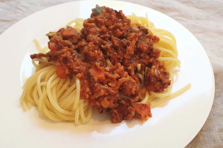 Spaghetti mit Bolognesesoße liegen auf einem weißen Teller.