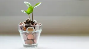 Symbol nachhaltige Bank: Aus einem Glas mit Münzen wächst eine kleine Pflanze