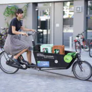 Eine Frau radelt auf einem Lastenrad durch die Stadt. Credits: fLOTTE Berlin