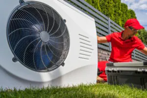 Ein Installateur kniet neben einer Wärmepumpe.