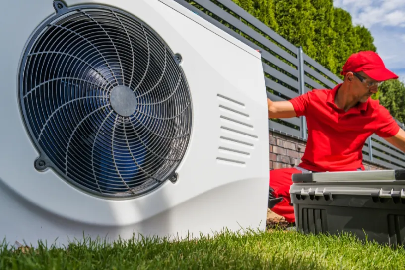 Ein Installateur kniet neben einer Wärmepumpe.